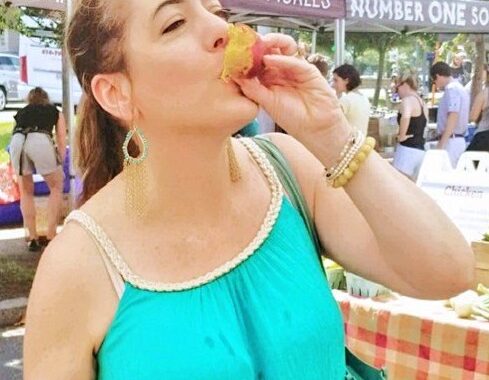 woman slurping eating peaches farmers market