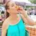 woman slurping eating peaches farmers market